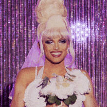 a woman in a bride 's dress is smiling and holding a bouquet of white flowers