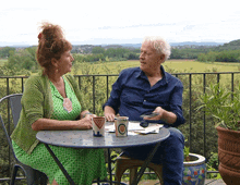 a man and a woman are sitting at a table with a cup that says ' o ' on it