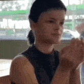 a young woman is sitting at a table with her hands folded in front of her face .