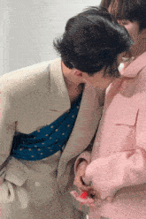 a man in a pink jacket kisses a woman on the cheek