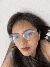 a woman wearing glasses is laying on a bed and looking at the camera .