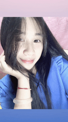 a woman wearing a blue shirt has her hand on her hair
