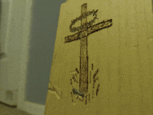 a cross is carved into a piece of wood with a nail sticking out of it