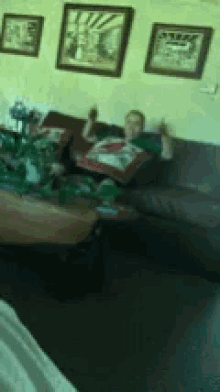 a man is sitting on a couch in a living room holding a bottle of beer .