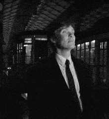 a man in a suit and tie stands in front of a bus