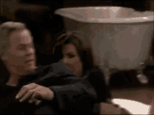 a man and a woman are sitting next to each other in front of a white sink .