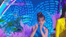 a woman in a blue dress is dancing on a stage with a yellow jacket .
