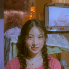 a girl in a pink sweater stands in front of a tv