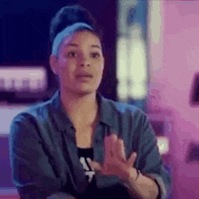a woman in a blue shirt is making a funny face while holding her hands together .
