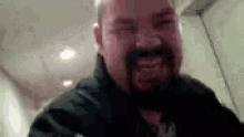 a man with a beard and mustache is making a funny face in a bathroom .
