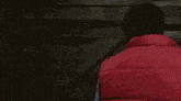 a man in a red vest looks out a window