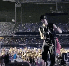 a man is standing on a stage playing a guitar in front of a crowd .
