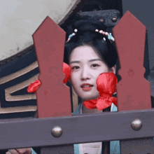 a woman behind a fence with red flowers on her face