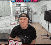 a man wearing headphones and a hat is sitting in front of a sign that says just for fun