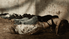 a group of people laying in the dirt with one wearing a black top that says ' s.m. ' on it