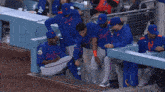 a group of new york mets baseball players sitting in the dugout