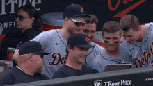 a group of detroit tigers players are sitting in the dugout looking at a tablet