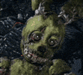 a close up of a green rabbit with a bloody face in a dark forest .