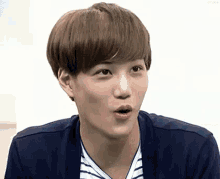 a young man with a surprised look on his face is wearing a striped shirt and a blue cardigan .