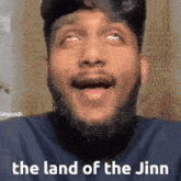 a man with a beard is making a funny face with the words `` the land of the jinn '' written below him .