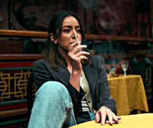 a woman smoking a cigarette while sitting at a table