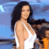 a woman is walking down a runway wearing a white one piece swimsuit with a plunging neckline