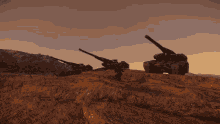 a couple of tanks sitting on top of a hill with mountains in the background