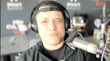a man wearing headphones stands in front of a mic