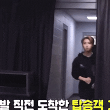 a man in a black hoodie is standing in a hallway with chinese writing on the wall