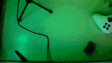 a green light is shining on a table with a xbox controller