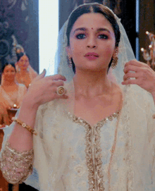 a woman in a white dress has a gold ring on her left hand