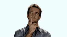 a man in a blue shirt is looking up with his hand on his chin