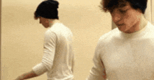 two young men are standing next to each other in a room .