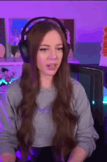 a woman wearing headphones is sitting in front of a computer and talking .