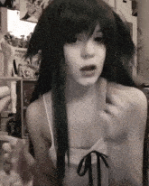 a black and white photo of a woman with long hair and a white tank top