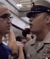 a man in a military uniform talks to another man with glasses