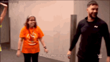 a man and woman are standing next to each other and the woman is wearing an orange shirt that says hi guys how are you