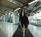 a woman in a suit is walking down a hallway holding a purse