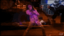 a man is singing into a microphone on a stage in front of a guitar player .