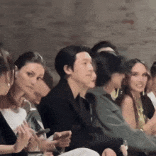 a group of people are sitting in a row with one woman holding a cell phone