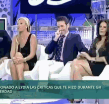 a group of people are sitting on a couch and one of them is talking on his phone