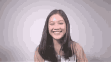 a young woman is smiling for the camera while wearing a brown shirt .