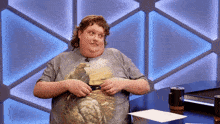 a man wearing a shirt with an eagle on it is standing in front of a table