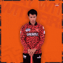 a man in a red and black shirt holds a ton cricket bat