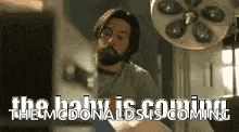 a man with a beard is standing in front of a mcdonald 's sign in an operating room .