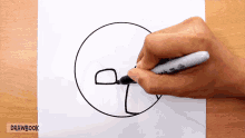 a person is drawing a circle with a sharpie marker on a piece of paper that says drawbook