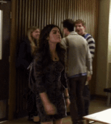 a woman in a floral dress stands in a room with people