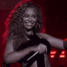 a woman with curly hair is smiling and flexing her muscles while wearing a black crop top