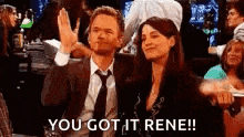 a man and a woman are sitting next to each other in a crowd . the man is giving the woman a high five .