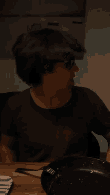 a man wearing glasses is sticking his tongue out while sitting at a table